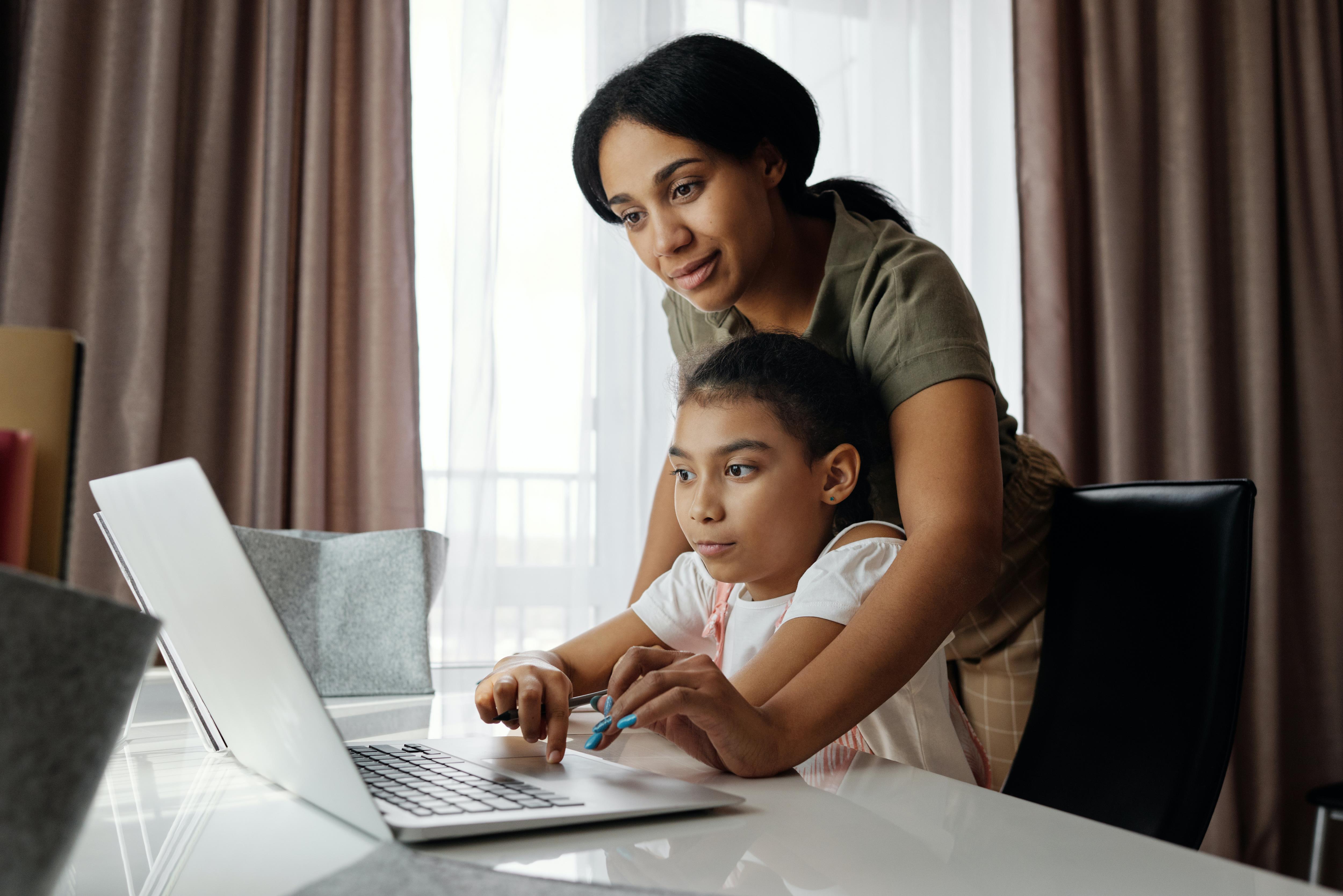 Parent helps child at computer