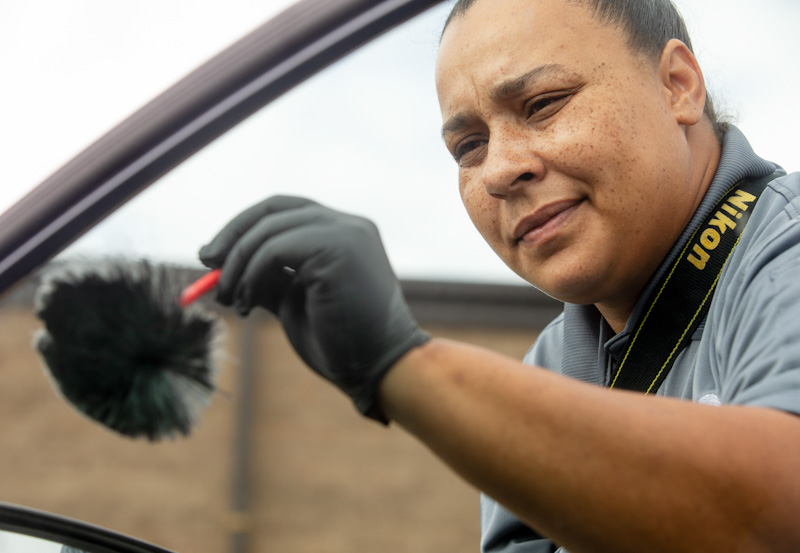 Greensboro Police Department CSI Kelli Wise dusts a car window for fingerprints.