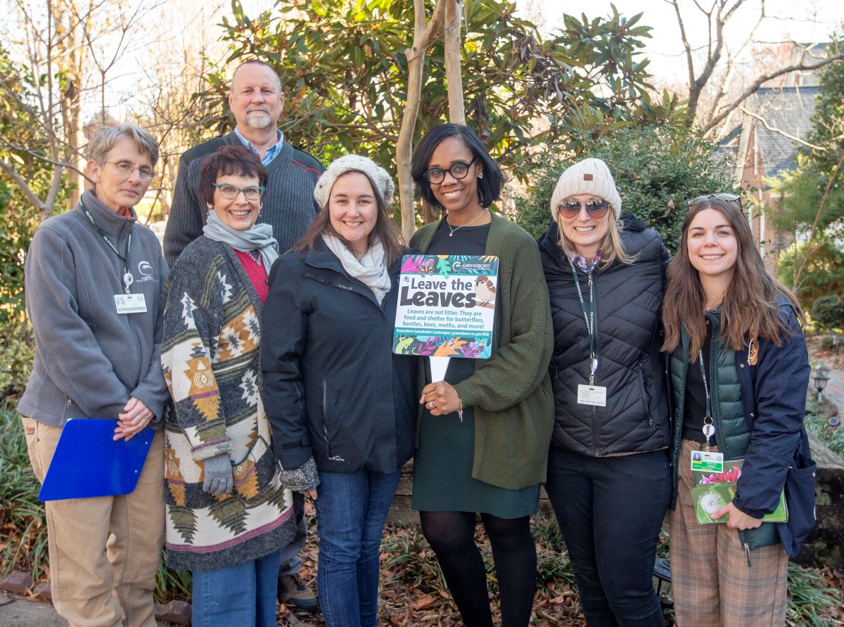 Group posing holding yard sign